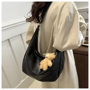 Detail of black soft leather hobo bag with a cute plush bear charm on a model