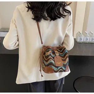Detail of a zigzag knit bucket bag with brown leather trim and drawstring closure