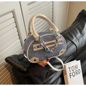 Close-up of denim barrel bag with beige leather trim and chunky silver metal chain detail