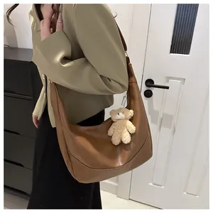 Brown semi-circle hobo shoulder bag in soft leather with a cute plush bear charm detail