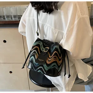 Close-up of bohemian wave pattern knit bucket bag with leather drawstring and logo label