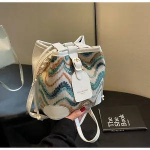 Detail of color-block tweed bucket bag with white leather trim and drawstring closure