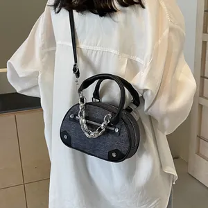 Mini grey denim crossbody bag with silver chain and black leather trim on model