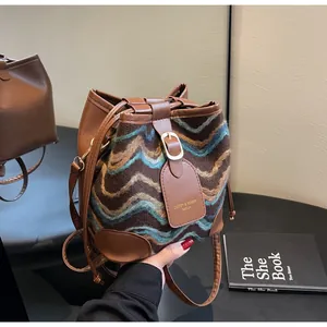 Detail of knit bucket bag with brown leather trim and wavy pattern design