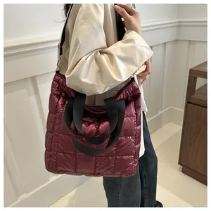 Detailed view of burgundy quilted tote bag with metallic finish and black straps