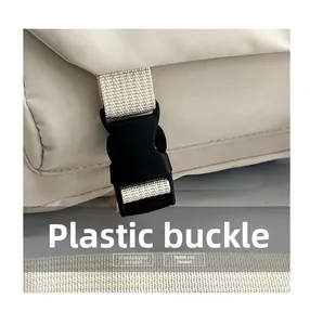 Dettaglio della fibbia in plastica e della tracolla in tessuto su borsa beige