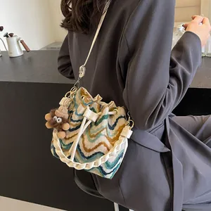 Bolso tipo cubo de punto bohemio con ondas, asa trenzada blanca y amuleto de peluche