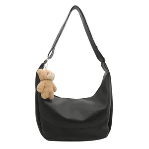 Minimalist black crescent shoulder bag in soft leather with a cute brown bear charm
