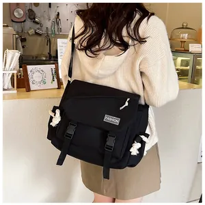Foto lifestyle di una borsa a tracolla in tela nera con etichette fashion e cinturino