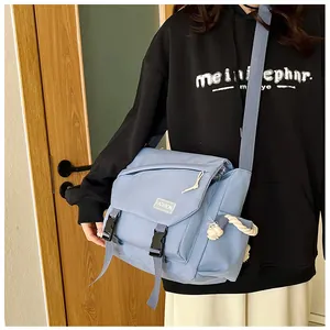 Dettaglio della borsa a tracolla in nylon azzurro con fibbia ed etichetta moda