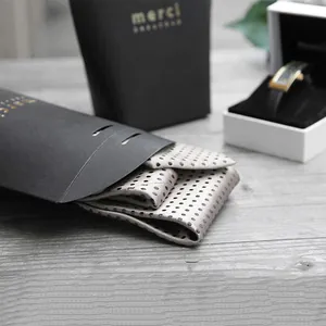 Elegant silver silk tie with dark dots in a black matte gift bag with gold merci logo