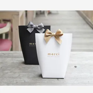 Elegant black and white gift bags with satin bows and golden merci beaucoup print