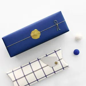 Navy gift box with gold wax seal and blue plaid pillow box set on white background