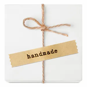 Detail of white gift box with rustic twine bow and handmade kraft paper sealing sticker