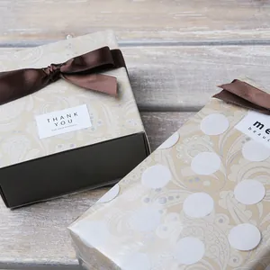 Close-up of paisley gift box with brown satin ribbon and a Thank You seal on wood