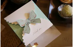 Detail view of mint green gift box with ribbon bow and gold Thank You lettering