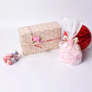 Detail of 20mm New Year ribbon with Happy New Year text on festive gift box and lace bag