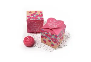 Close-up of pink strawberry gift box with heart closure and rose-shaped candle