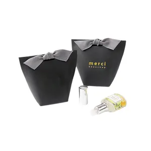 Minimalist black trapezoid gift box set with grey ribbon bow and gold merci inscription