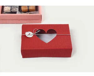 Macro detail of red corrugated gift box with heart window and decorative silver cord tag