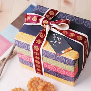 Détail du coffret cadeau coréen avec rayures colorées et ruban estampé à l'or brillant
