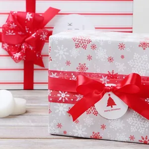 Christmas gift box wrapped with white snowflake paper and wide red satin ribbon