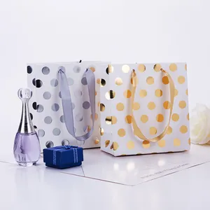 Detail of paper gift bags with gold and silver foil polka dots and elegant silk handles