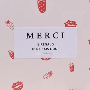 Close-up of rectangular chocolate stickers with red strawberries, lips, and Merci text