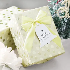 Detail of light yellow satin ribbon bow and Merry Christmas tag on gift box packaging