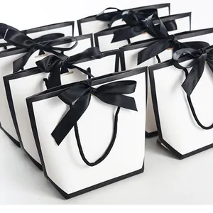 Elegante weiße Geschenktüten in Trapezform mit schwarzem Rand und Satin-Schleife