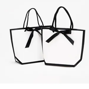 Minimalistische weiße Geschenktüte aus Papier mit schwarzem Rand und großer Seidenschleife