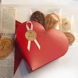 Coffret cadeau rouge en forme de cœur avec ruban blanc et pâtisseries sur fond vintage