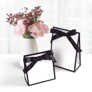 Minimalist white gift paper bags with black ribbon bows and elegant floral decor