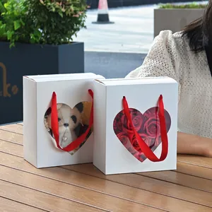 Square white gift boxes with heart window and red silk ribbon handles for Valentine's Day