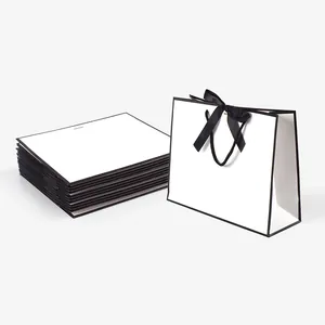 Minimalist white paper gift bag with black border and silk ribbon bow handles