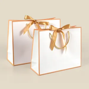 Minimalist white paper shopping gift bag with orange trim and golden ribbon bow