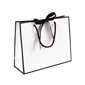 Minimalist white paper gift bag with black border and silk ribbon for boutique shopping