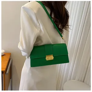 Close-up of green shoulder bag with gold clasp shown on model with white blazer