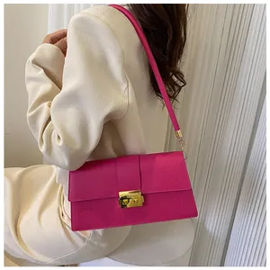 Close-up of bright pink faux crocodile shoulder bag with golden square metal buckle