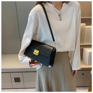 Detail of black crocodile texture handbag with golden square buckle and fine shoulder strap