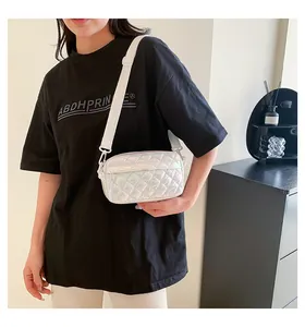 Detailansicht einer irisierenden weißen Stepptasche mit breitem Textilschultergurt