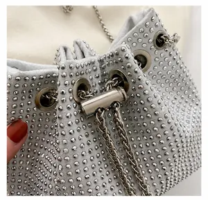 Detail van zilveren strass emmertas met trekkoordsluiting en metalen kettingriem