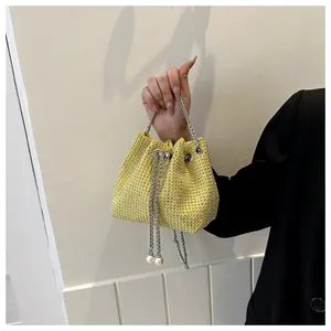 Gele emmertas met sprankelende strass-steentjes, zilveren ketting en pareldetails