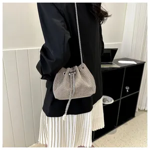 Detail van zilveren strass-emmer tas met trekkoord parels en ketting schouderriem