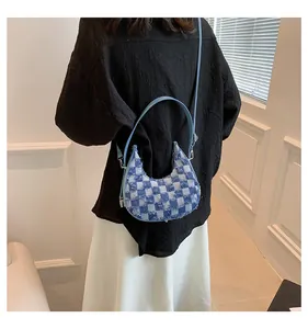 Rear view of a model wearing a blue checkered crescent denim bag with frayed edges
