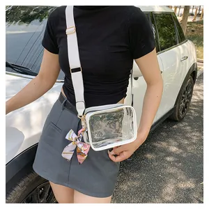 Detailed shot of a clear PVC crossbody bag with white leather trim and floral silk scarf