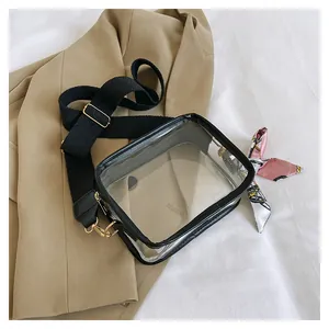 Detail of transparent PVC crossbody bag with wide shoulder strap and pink decorative scarf