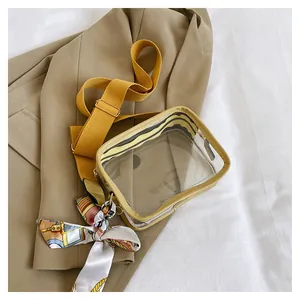Detail of transparent PVC crossbody bag with mustard yellow strap and floral scarf decor
