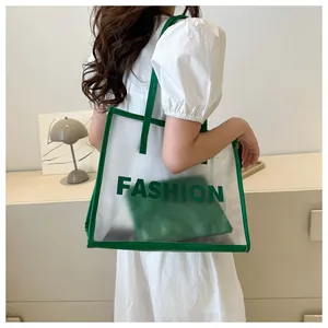 Detail view of large transparent PVC tote bag with green trim and matching inner pouch