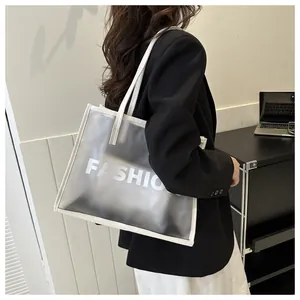 Detail of a semi-transparent white tote bag with FASHION print and white leather trim